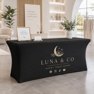 Peut inclure: Une nappe extensible noire ornée d'un logo doré représentant un croissant de lune, des fleurs et des étoiles. Le texte indique LUNA & CO EVENT TABLE COVER, accompagné des icônes des réseaux sociaux Facebook, Instagram, TikTok et YouTube.