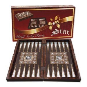 Puede incluir: Un juego de backgammon de madera con una superficie de juego marrón oscuro y patrones decorativos incrustados. El juego está abierto, revelando el tablero con puntas triangulares y un diseño central. La caja presenta las palabras "Star" y "Masif Sedef Tavla".