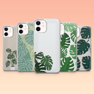May include: Five clear phone cases with various green monstera leaf designs. The cases feature different shades of green and white, with a light peach background. One case has a potted plant design.