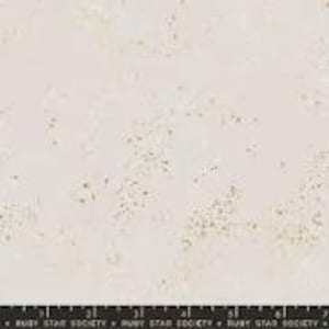 May include: Cream-colored fabric with a subtle, speckled pattern in gold. The fabric is marked with a black ruler along the bottom edge, showing measurements in inches. The text "RUBY STAR SOCIETY" is printed along the ruler.