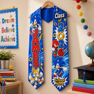 May include: A blue graduation stole featuring Sonic the Hedgehog and other characters. The stole has the name "JAMES" in red letters and "Class of 2026" with space for a school name. The design includes stars and lightning bolts.