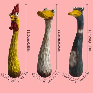May include: Three tall, slender animal figurines with textured surfaces. The left is a yellow rooster with a red comb. The middle is a white duck with a yellow beak. The right is a dark gray duck with a yellow beak. Heights are 6.88 inches and 6.10 inches.