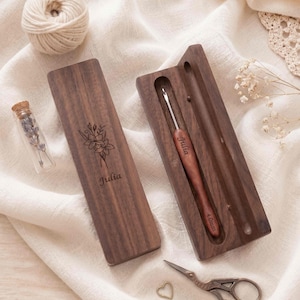 Peut inclure: Un étui en bois brun foncé avec une gravure florale et le nom Julia, contenant un crochet en bois assorti marqué 4.0mm et Julia. L'étui est rectangulaire avec un couvercle coulissant, et le crochet présente une pointe en métal argenté.