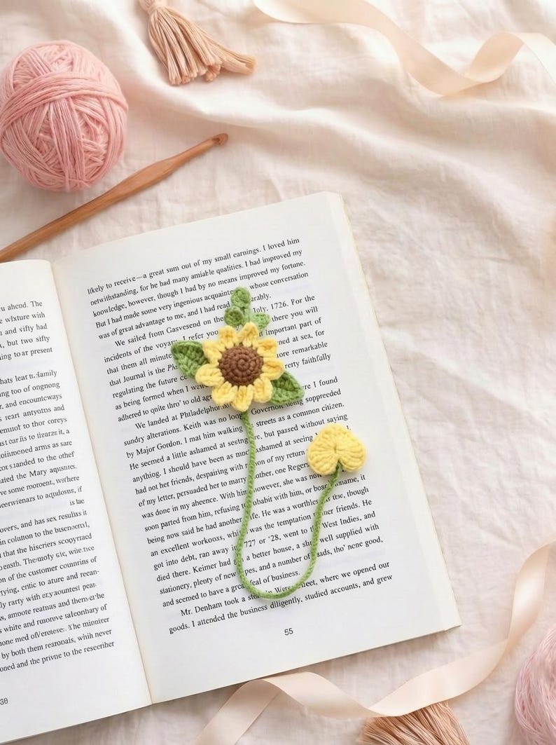 Puede incluir: Marcap&aacute;ginas de girasol de ganchillo hecho a mano con flor amarilla y hojas verdes, sobre un libro abierto. Un accesorio encantador para los amantes de la lectura, que a&ntilde;ade un toque artesanal a la lectura.