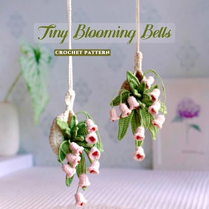 Puede incluir: Dos flores de ganchillo en forma de campana, suspendidas por cuerdas blancas. Las flores son rosas con detalles rojos, rodeadas de hojas verdes. El texto "Tiny Blooming Bells" y "CROCHET PATTERN" se muestra en la imagen.