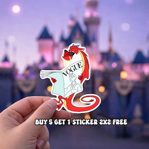 May include: A sticker featuring a red dragon wearing sunglasses and reading a magazine with the word "VOGUE" on the cover. The dragon is a cartoon character. The sticker is held in a hand against a blurred background.