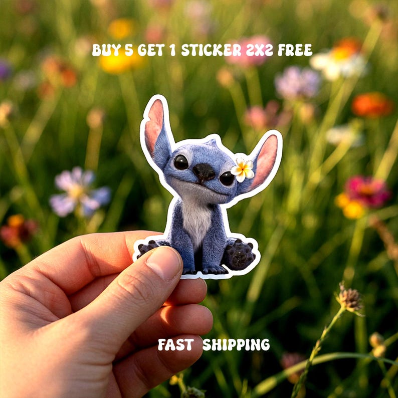 May include: A blue cartoon character sticker with a white flower on its ear. The sticker is held in a hand against a blurred background of flowers. Text on the sticker reads "BUY 5 GET 1 STICKER 2X2 FREE".