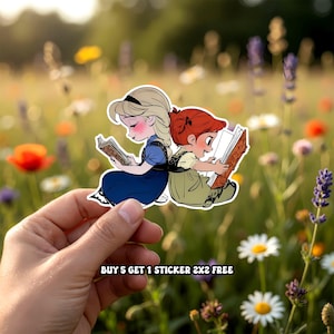 Peut inclure: Un autocollant repr&eacute;sentant deux jeunes filles de dessin anim&eacute; lisant des livres, l'une portant une robe bleue et l'autre une robe verte. Le texte "BUY 5 GET 1 STICKER 2x2 FREE" est inclus. Le fond est un champ de fleurs.