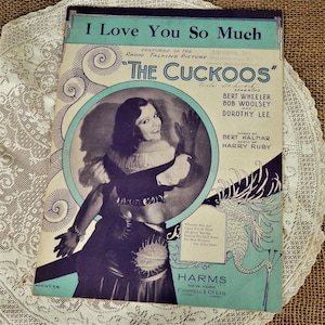 May include: A vintage sheet music cover for the song "I Love You So Much" from the musical "The Cuckoos." The cover features a black and white photograph of a woman in a costume, with a blue and green illustration of a bird in the background. The text "I Love You So Much" is printed in large, bold letters at the top of the cover.