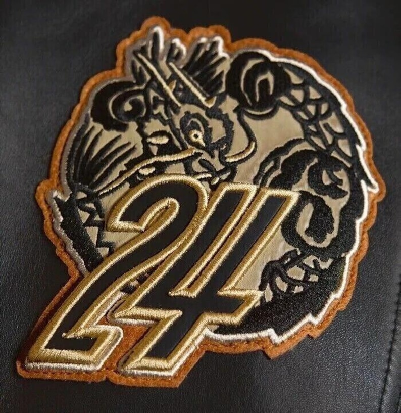 May include: Embroidered patch featuring a dragon design with the number 24. The patch has a black and gold color scheme with a brown border. The dragon is intricately detailed, and the number is outlined in gold.