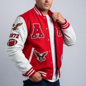 May include: Red and white varsity jacket with the letter "A" and eagle patches. The jacket has white sleeves, a red body, and a striped collar and cuffs. A football patch and the number "1972" are also visible.