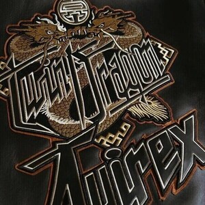 May include: Embroidered patch featuring two golden dragons above the words "Twin Dragon" and "Avirex" in a bold, stylized font. The patch has a black background with brown and white accents, creating a striking contrast.