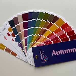 Könnte beinhalten: Ein Farbfächer mit einer Auswahl an Herbsttönen. Der Fächer enthält Farbmuster in Gelb-, Orange-, Rot-, Rosa-, Grün- und Lilatönen. Der Fächer trägt die Aufschrift "Autumn" und den Text "Oxford Lawrence".