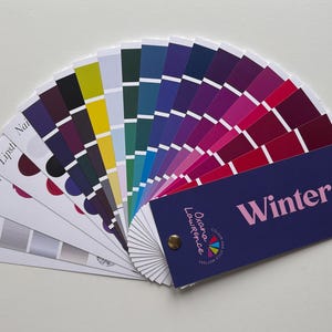May include: A colour palette fan displaying a range of hues, including pinks, purples, blues, greens, and yellows. The fan is labelled "Winter" and features the name "Oxana Lawrence".