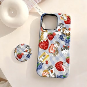 May include: A rectangular phone case and a circular phone grip featuring a light blue gingham pattern decorated with illustrations of small kittens, red strawberries, and blueberries. The kittens are shown interacting with the fruit and cake slices.