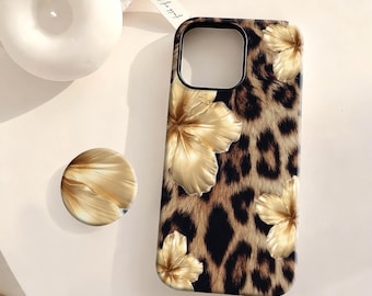 Peut inclure: Coque de téléphone avec un motif léopard et des fleurs d'hibiscus dorées. Un support de téléphone doré assorti est également présent. L'étui est conçu pour un smartphone, offrant un accessoire élégant et protecteur.