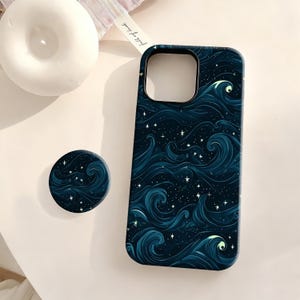 May include: A dark blue phone case and matching phone grip featuring a swirling wave and star pattern. The case has a camera cutout and the grip is round. The design is reminiscent of a starry night sky.