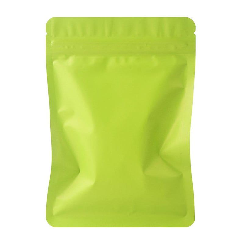 May include: A bright lime green, sealed, stand-up pouch. The pouch is empty and has a zip-top closure. The material is shiny and reflects light. The bag is designed for packaging food items or other small products.