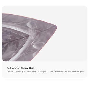 May include: Close-up of a silver foil bag with a secure zip closure. The bag's interior is visible, and the text "Foil Interior. Secure Seal" is displayed. The bag is designed to be resealed for freshness and dryness.