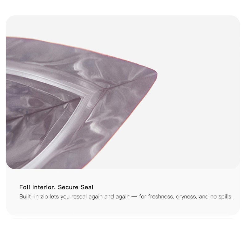May include: Close-up of a silver foil bag with a secure zip closure. The bag's interior is visible, and the text "Foil Interior. Secure Seal" is displayed. The bag is designed to be resealed for freshness and dryness.