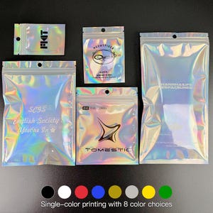 May include: A collection of iridescent, holographic zip-lock bags in various sizes. Some bags feature text and logos, including "FIAT", "MEOWSPIDER", "SCYSIS English Society. You're In", "TOMESTIC", and "HANWHA LIFE ESPACELINES". The bottom of the image shows color options for single-color printing.