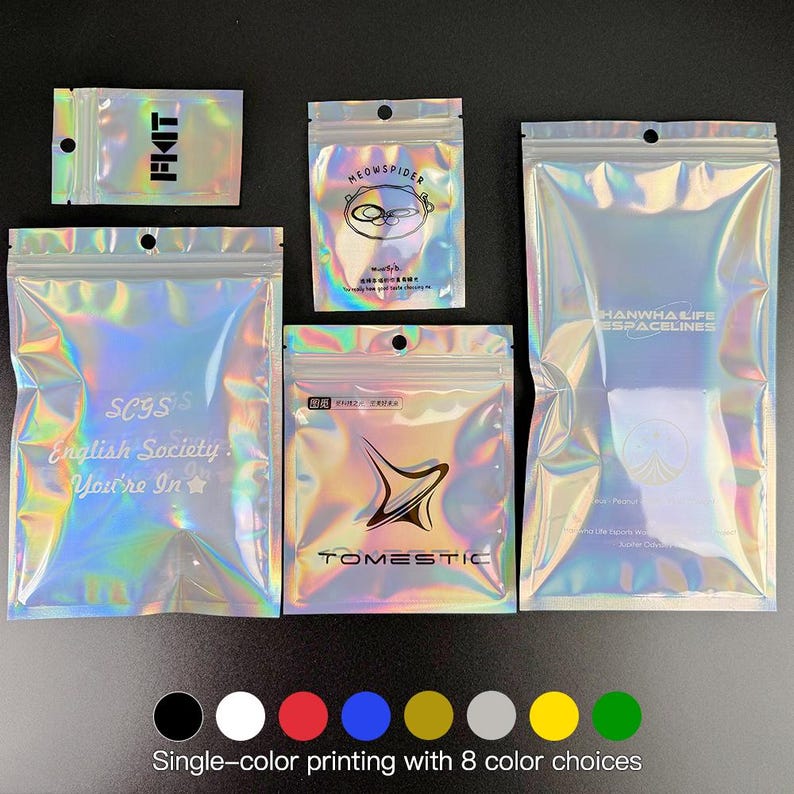 May include: A collection of iridescent, holographic zip-lock bags in various sizes. Some bags feature text and logos, including "FIAT", "MEOWSPIDER", "SCYSIS English Society. You're In", "TOMESTIC", and "HANWHA LIFE ESPACELINES". The bottom of the image shows color options for single-color printing.
