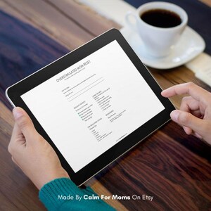 May include: A black tablet displaying a document titled "OVERSTIMULATED MOM RESET" with bullet points. The tablet is held by a person, with a cup of coffee in the background. The text "Made By Calm For Moms On Etsy" is at the bottom.