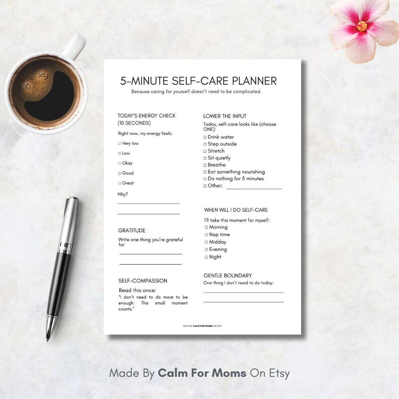 May include: A white 5-Minute Self-Care Planner with sections for energy checks, gratitude, and self-compassion. Includes a pen, a cup of coffee, and a flower. The planner is designed to simplify self-care routines.