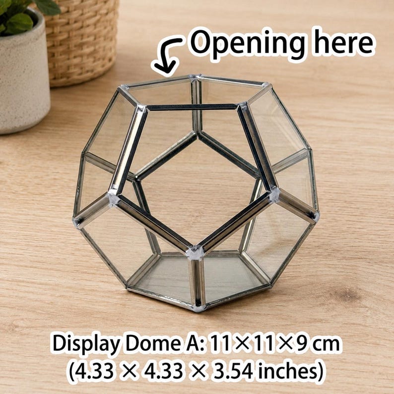May include: A geometric glass terrarium with a metal frame, featuring an open top labeled with the text Opening here. The display dome measures 4.33 x 4.33 x 3.54 inches. The structure consists of clear glass panels joined by dark metal edges.