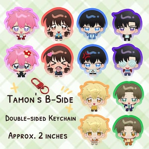 May include: A collection of twelve double-sided acrylic keychains featuring chibi-style anime characters with various expressions and colored outlines. A red metal lobster clasp is included. Text reads: Tamon's B-Side, Double-Sided Keychain, Approx. 2 inches.