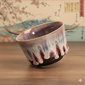 Peut inclure: Une tasse à thé en céramique au design unique. La tasse présente une base marron foncé, passant à un motif marbré blanc et violet, avec un bord marron clair. La tasse est inclinée, mettant en valeur ses détails intérieurs et extérieurs.