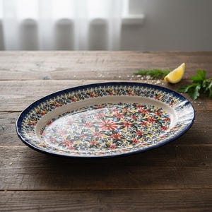 May include: An oval ceramic serving platter with a floral pattern. The platter has a dark blue rim and is decorated with red, yellow, and blue flowers on a white background. The platter is approximately 14 inches long.