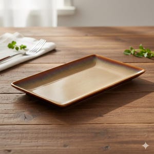 Könnte beinhalten: Ein rechteckiger Keramik-Servierteller mit glänzendem Finish. Der Teller hat ein Farbverlauf, der von einer hellbraunen Mitte zu einem dunkleren braunen Rand übergeht. Der Teller steht auf einer Holzoberfläche.