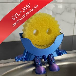 May include: A blue 3D-printed sponge holder with a smiling face design, holding a yellow sponge. The holder has legs and feet, and the text "STL + 3MF DIGITAL DOWNLOAD" is visible on a red banner. The sponge holder is placed in a sink.