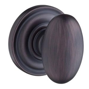 May include: A bronze-colored door knob with an oval handle and a circular backplate. The knob has a brushed metal finish, and the backplate features a raised, decorative edge. This hardware is suitable for interior doors.