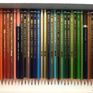 K&ouml;nnte beinhalten: Eine Sammlung angespitzter Farbstifte, die in einer Reihe angeordnet sind. Die Stifte sind in verschiedenen Farben, darunter Gelb, Orange, Rot, Blau und Gr&uuml;n. Auf jedem Stift ist der Markenname "Faber-Castell" aufgedruckt.
