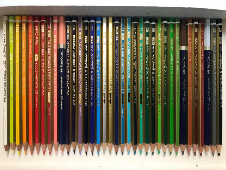 K&ouml;nnte beinhalten: Eine Sammlung angespitzter Farbstifte, die in einer Reihe angeordnet sind. Die Stifte sind in verschiedenen Farben, darunter Gelb, Orange, Rot, Blau und Gr&uuml;n. Auf jedem Stift ist der Markenname "Faber-Castell" aufgedruckt.