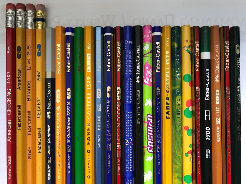 May include: A collection of pencils of various colors and designs, including red, yellow, green, and blue. The pencils are from the Faber-Castell brand and feature text such as "American Checking 1007" and "Fashion". The pencils have erasers.