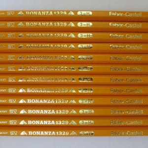 May include: A collection of twelve yellow hexagonal pencils arranged in parallel. Each pencil features gold foil text reading GERMANY, SV, BONANZA 1329, 3=H, and Faber-Castell. The pencils have a smooth finish and a consistent, uniform appearance.