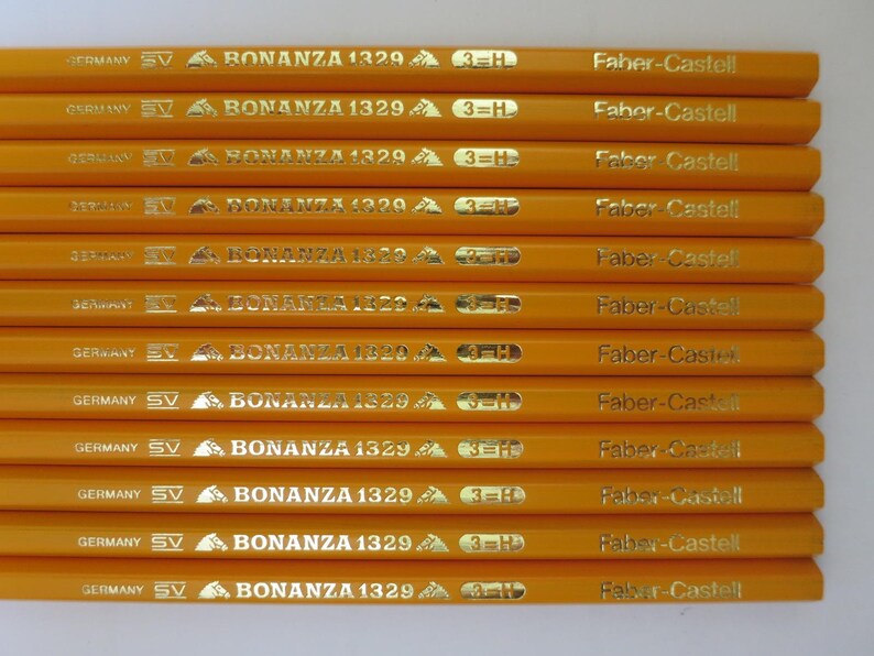 May include: A collection of twelve yellow hexagonal pencils arranged in parallel. Each pencil features gold foil text reading GERMANY, SV, BONANZA 1329, 3=H, and Faber-Castell. The pencils have a smooth finish and a consistent, uniform appearance.