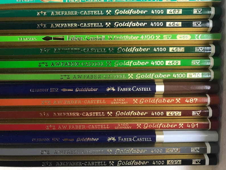 K&ouml;nnte beinhalten: Nahaufnahme einer Sammlung von Faber-Castell Goldfaber Bleistiften. Die Bleistifte sind in verschiedenen Farben, darunter Gr&uuml;n, Blau, Orange und Braun. Jeder Bleistift ist mit dem Markennamen Goldfaber und einer Nummer beschriftet.