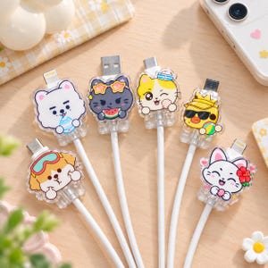 May include: Six white USB charging cables featuring clear acrylic character covers. The designs include a white dog with goggles, a white bear, a black cat with star glasses eating watermelon, a yellow cat with a sailor hat, a yellow duck with sunglasses, and a white cat with a red flower.