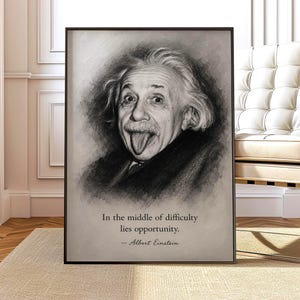 May include: A framed black and white portrait print of Albert Einstein sticking his tongue out. Below the portrait, the text reads: In the middle of difficulty lies opportunity. — Albert Einstein. The artwork is presented in a dark frame.