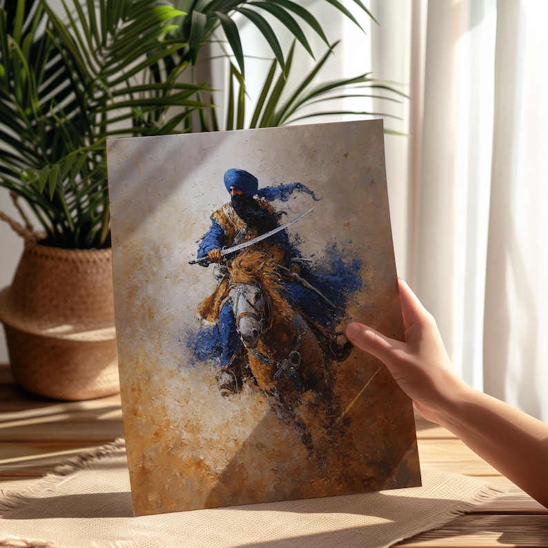 May include: An artistic print showing a warrior on horseback with a sword. The warrior wears blue and gold clothing and a blue turban. The artwork uses brown, blue, and gold tones, giving a dynamic and historical feel. The print is held by a person.