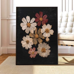 May include: A framed art print featuring a collection of pressed flowers against a black background. The flowers are in shades of white, pink, and brown, with yellow centers. The artwork is displayed in a black frame, suitable for home decor.
