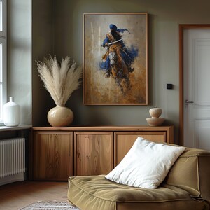 May include: A framed print shows a figure on horseback, in blue, brown, and gold tones. It hangs above a wooden cabinet, with a vase of dried pampas grass and a white cushion on a green sofa. The room has a neutral colour scheme.