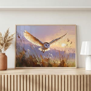 May include: A framed painting depicting a barn owl in flight against a sunset backdrop. The owl's wings are outstretched, showcasing its white and tan plumage. The artwork includes a field of tall grass and a sky with purple, orange, and yellow hues.