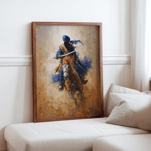 May include: A framed art print showing a warrior on horseback, painted in a loose style. The figure is in blue clothing and a turban, holding a sword. The horse is brown, set against a background of warm, earthy colours.