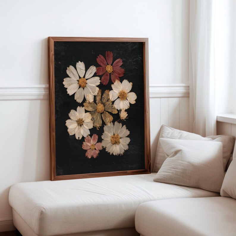 May include: A framed botanical print featuring pressed flowers in shades of white, cream, and burgundy against a dark background. The flowers are arranged in a cluster within a wooden frame, creating a natural and elegant aesthetic.
