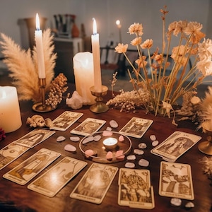 May include: A wooden table displays a tarot card reading setup. Lit candles in brass holders and a central candle illuminate the scene. Tarot cards are arranged with scattered rose quartz crystals and dried flowers, creating a mystical ambiance.